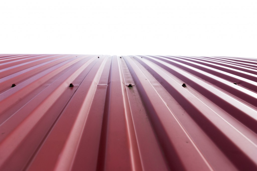 Rooftop of curved red corrugated iron on white background