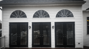 A home with white siding and three sets of black French doors.